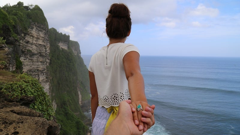 A woman and man holding hands by the ocean