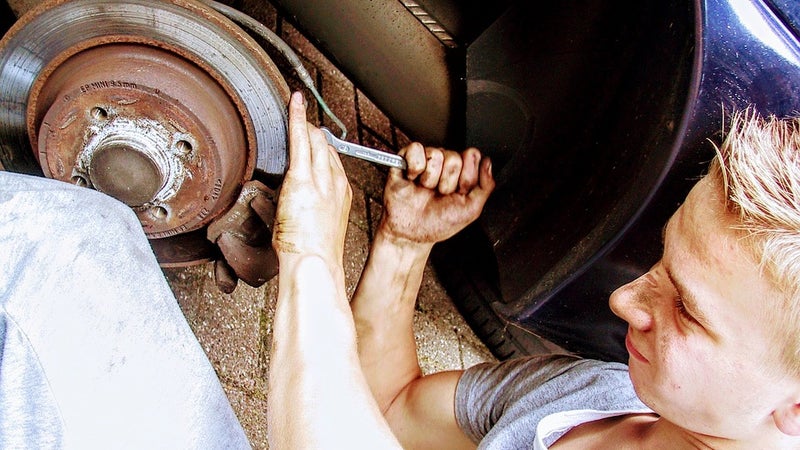 A young man using a wrench to work on a car
