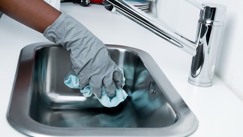 A person wearing gloves cleaning a sink