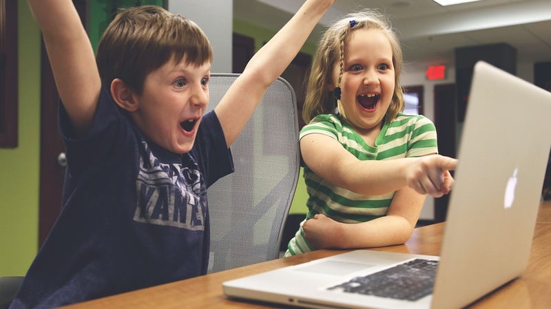 Two children playing a game on a laptop