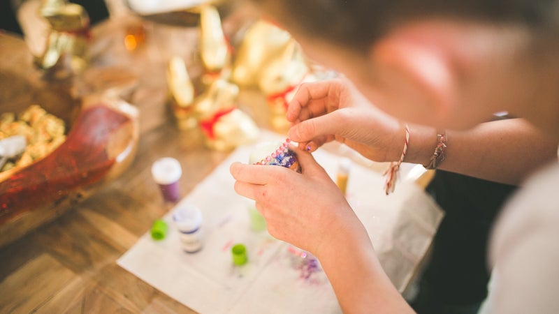 A girl crafting using beads and glue